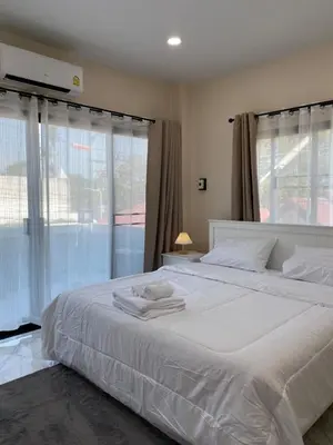 a bedroom with a large white bed with windows at Ta-iad homestay in Ban Suan