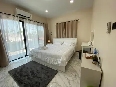 a bedroom with a white bed and a large window at Ta-iad homestay in Ban Suan