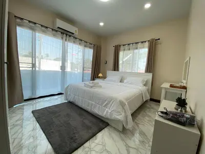 a bedroom with a white bed and a large window at Ta-iad homestay in Ban Suan