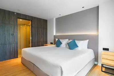 a bedroom with a large white bed with blue pillows at Super Studio La Vita 2 pool in Rawai Beach
