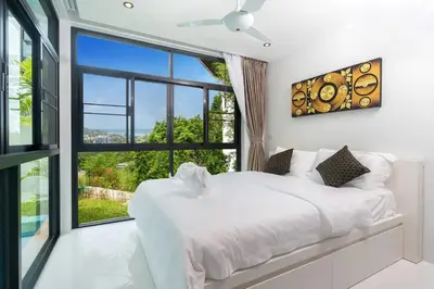 a bedroom with a white bed and a large window at Namara The Residences B in Kamala Beach