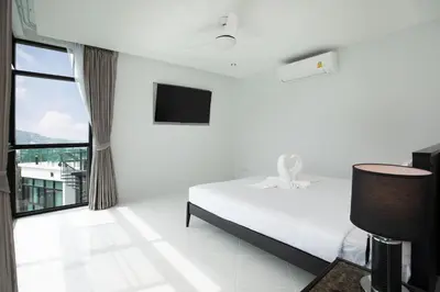 a white bedroom with a bed and a tv at Namara The Residences B in Kamala Beach