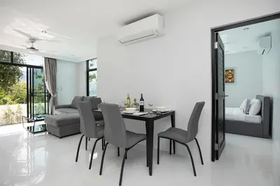 a dining room with a table and chairs and a couch at Namara The Residences B in Kamala Beach