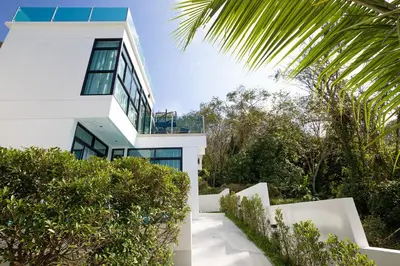a white house with trees and bushes at Namara The Residences B in Kamala Beach