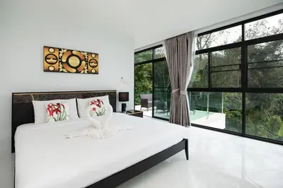 a white bedroom with a large bed and large windows at Namara The Residences B in Kamala Beach