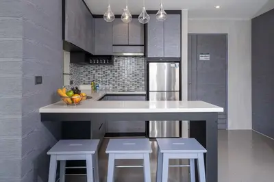 a kitchen with a white counter and stools in it at Tropical Pool View 2 BR Apartment CTG B207-8 in Tropics Kamala Residence in Kamala Beach
