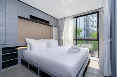 a bedroom with a large white bed with a window at Tropical Pool View 2 BR Apartment CTG B207-8 in Tropics Kamala Residence in Kamala Beach