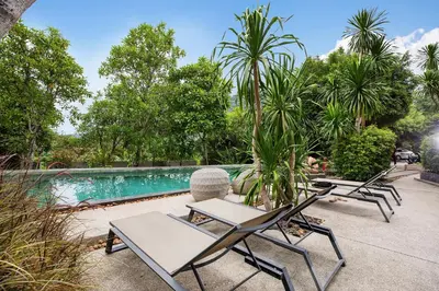 a group of lounge chairs next to a swimming pool at Embrace Nature, Comfort & Beach Proximity - Natural Park B24 Suite, Kamala in Kamala Beach