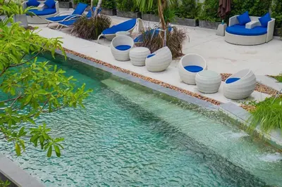 a swimming pool with blue chairs and a pool of water at Embrace Nature, Comfort & Beach Proximity - Natural Park B24 Suite, Kamala in Kamala Beach