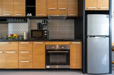 a kitchen with wooden cabinets and a stainless steel refrigerator at Embrace Nature, Comfort & Beach Proximity - Natural Park B24 Suite, Kamala in Kamala Beach