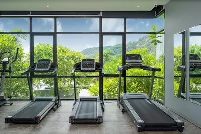 a gym with three treadmills in front of a large window at Embrace Nature, Comfort & Beach Proximity - Natural Park B24 Suite, Kamala in Kamala Beach