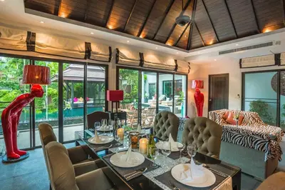 a dining room with a table and chairs and a room with windows at 06 - Luxurious & Lavish Getaway in Surin Beach in Surin Beach