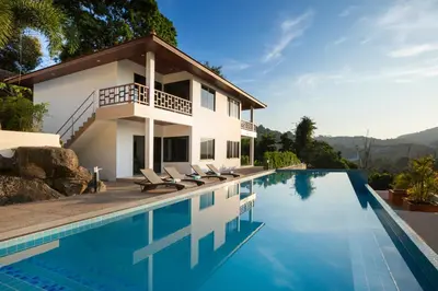 a villa with a swimming pool and a house at Baan Chom View Residences in Kamala Beach