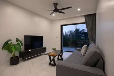 a living room with a couch and a flat screen tv at Baan Chom View Residences in Kamala Beach