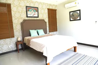a bedroom with a bed and two pictures on the wall at Naiharn Beach 3 bedrooms villa in Rawai Beach