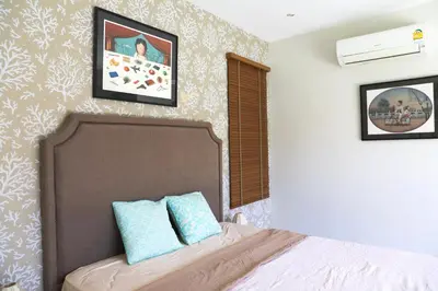 a bedroom with a bed and two pictures on the wall at Naiharn Beach 3 bedrooms villa in Rawai Beach