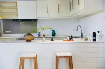 a kitchen with white cabinets and a counter with two stools at Naiharn Beach 3 bedrooms villa in Rawai Beach