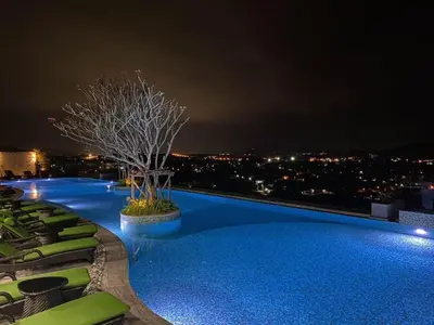 a swimming pool at night with a tree on the roof at Condo with Roof top sea view in Rawai Beach