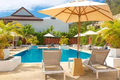 a swimming pool with chairs and an umbrella and a pool at Naiharn beach sands Apartment in Nai Harn Beach