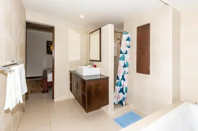 a bathroom with a sink and a mirror and a shower at Naiharn beach sands Apartment in Nai Harn Beach