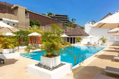 a swimming pool with a palm tree in the middle at Naiharn beach sands Apartment in Nai Harn Beach