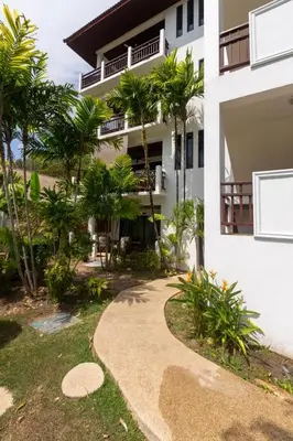 a walkway in front of a house with palm trees at Naiharn beach sands Apartment in Nai Harn Beach