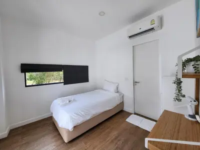 a white bedroom with a bed and a window at Zen House Mono in Ban Na Bon
