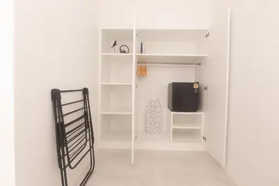 a room with white walls and a tv and shelves at Place Hotel in Kata Beach