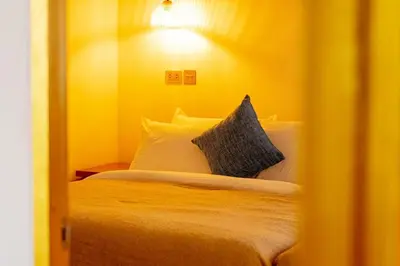 a bedroom with a bed with yellow walls and pillows at The beach house in Surin Beach