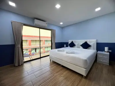 a bedroom with a large bed and a large window at Kata walk&wave hostel in Kata Beach