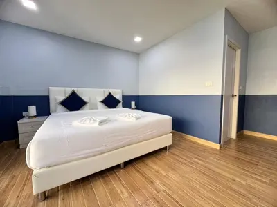 a bedroom with a large white bed with blue walls at Kata walk&wave hostel in Kata Beach
