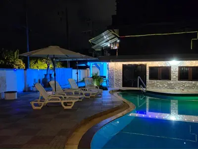 a swimming pool at night with chairs and an umbrella at Baan Nur Nur 201 in Surin Beach