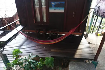 a hammock on a wooden porch with a door at Tropical Hostel in Phi Phi Don
