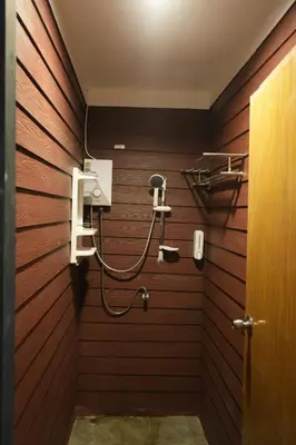a shower in a bathroom with a wooden wall at Tropical Hostel in Phi Phi Don
