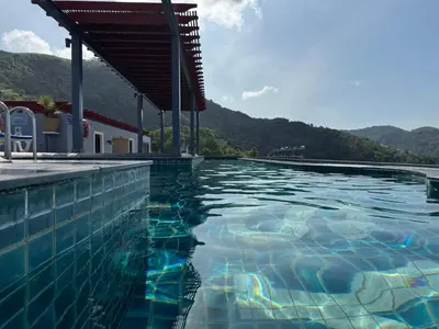 a swimming pool with blue water and mountains in the background at Luxury Seaview studio apartment at Karon beach in Karon Beach