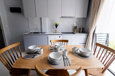 a kitchen with a wooden table with plates and utensils at SPACIOUS AND BRIGHT 2BR TownHouse7 MonkeyHill in Ban Sam Kong