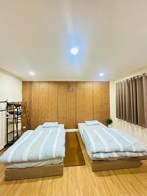 two beds in a room with a wall at Dedbaicha cafe & Hostel Phuket old town in Phuket Town