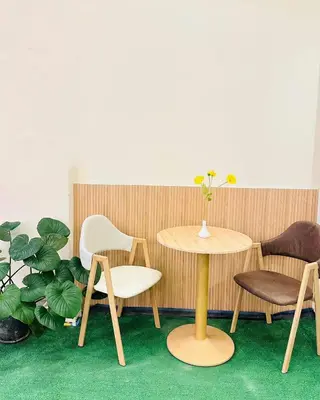 a table and chairs in a room with a plant at Dedbaicha cafe & Hostel Phuket old town in Phuket Town