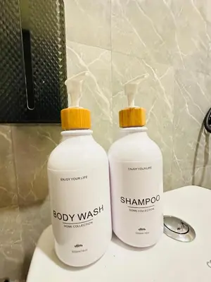 two bottles of baby wash sitting on a bathroom sink at Dedbaicha cafe & Hostel Phuket old town in Phuket Town
