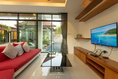 a living room with a red couch and a flat screen tv at V172 Siena Villa Stunning 3-Bedroom & Private Pool in Kata Beach
