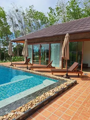 a swimming pool with two umbrellas next to a house at Bulan Villa Koh Yao Noi in Ban Laem Sai