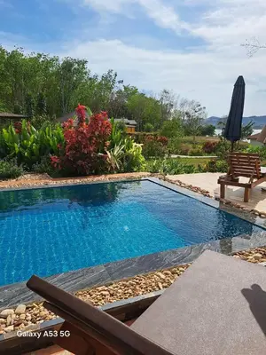 a swimming pool in a yard with a bench and flowers at Bulan Villa Koh Yao Noi in Ban Laem Sai