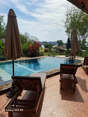 a swimming pool with two umbrellas and two chairs at Bulan Villa Koh Yao Noi in Ban Laem Sai