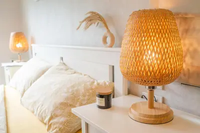 a lamp sitting on a table next to a bed at Lovely Vlada in Nai Yang Beach