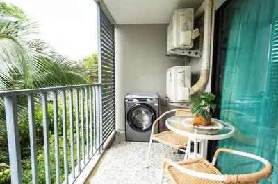 a balcony with a washing machine and a table and chairs at Lovely Vlada in Nai Yang Beach