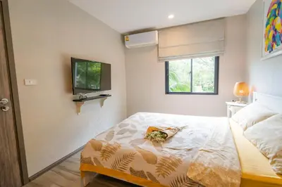 a bedroom with a bed and a tv on the wall at Lovely Vlada in Nai Yang Beach