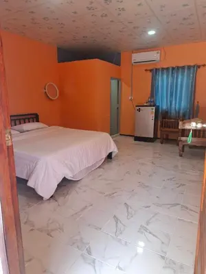 a bedroom with a bed and orange walls and a marble floor at Fadel Residence in Ko Yao Yai
