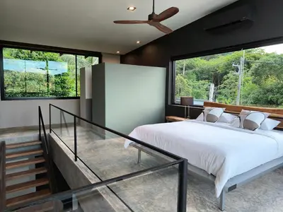 a bedroom with a large bed with a large window at Sky Lofts Airport Phuket in Nai Yang Beach