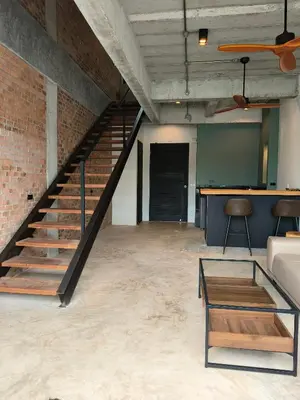 an industrial loft with a staircase and a table at Sky Lofts Airport Phuket in Nai Yang Beach