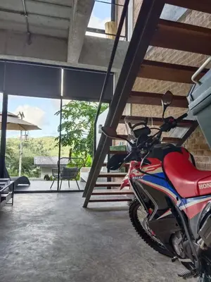 a red motorcycle parked in a room with a patio at Sky Lofts Airport Phuket in Nai Yang Beach